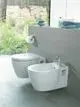 Weißes Wandbidet von Ideal Standard mit integriertem Wasserhahn. Im Hintergrund ein modernes Badezimmer mit großen Fenstern und Gartenblick.